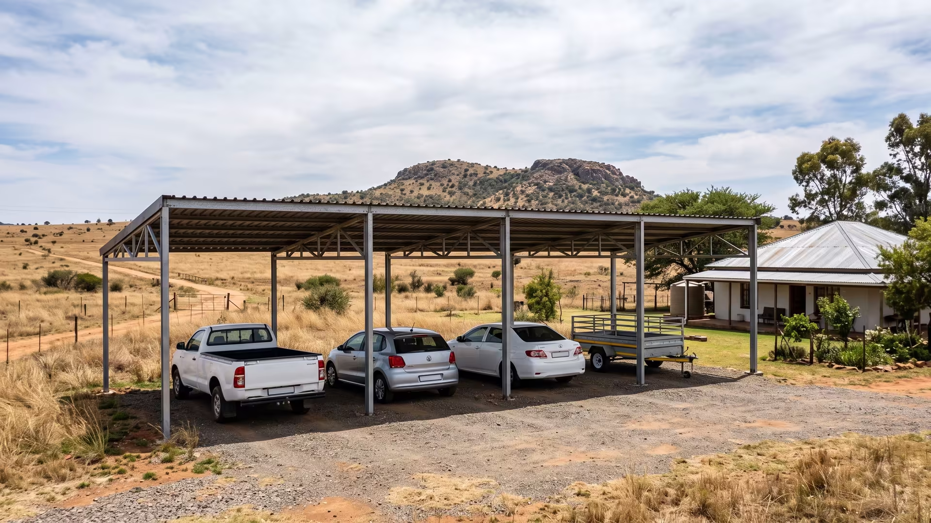 Long-span four-bay steel carport on a Muldersdrift smallholding with open Highveld grassland behind